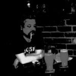 The author, when he smoked, sitting in a bar with two glasses of cloudy cider in front of him.