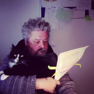 The author and his cat. One of them is proofing a document. You can tell his by the yellow sticky notes hanging off the paper in his hand.