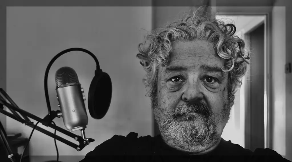 The author when he was properly scruffy, all beard and curly hair. He's sitting next top a microphone.