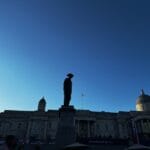A silhouette of a figures in a hat shot against a darkening blue sky,