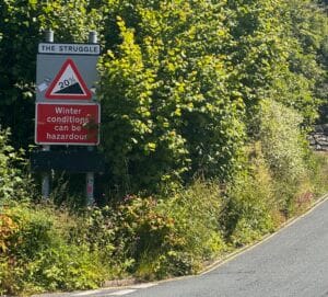 There's a steep climb near Ambleside in NW England's Lake District. It's called The Struggle. This image shows the name and its 20% incline. Another sign reads 'Winter conditions can be hazardous'