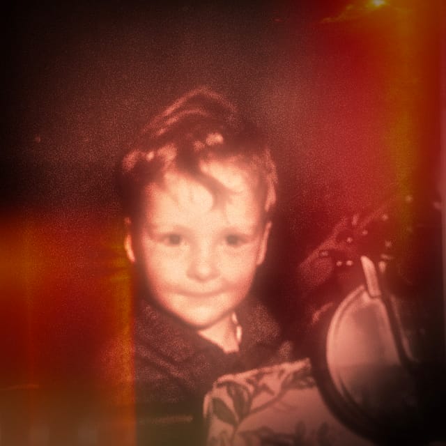 A young boy with a toy Tommy gun. He looks demonic.