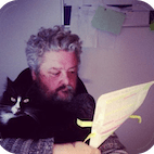 Tim and Sydney the cat. Tim is reading a document.