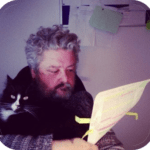 Noel and Sydney the cat. Noel is marking up a paper. Syd' is looking at you.