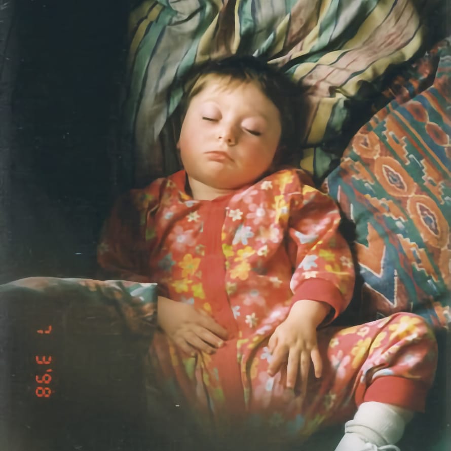 My daughter Zuzu asleep on a pile of cushions.